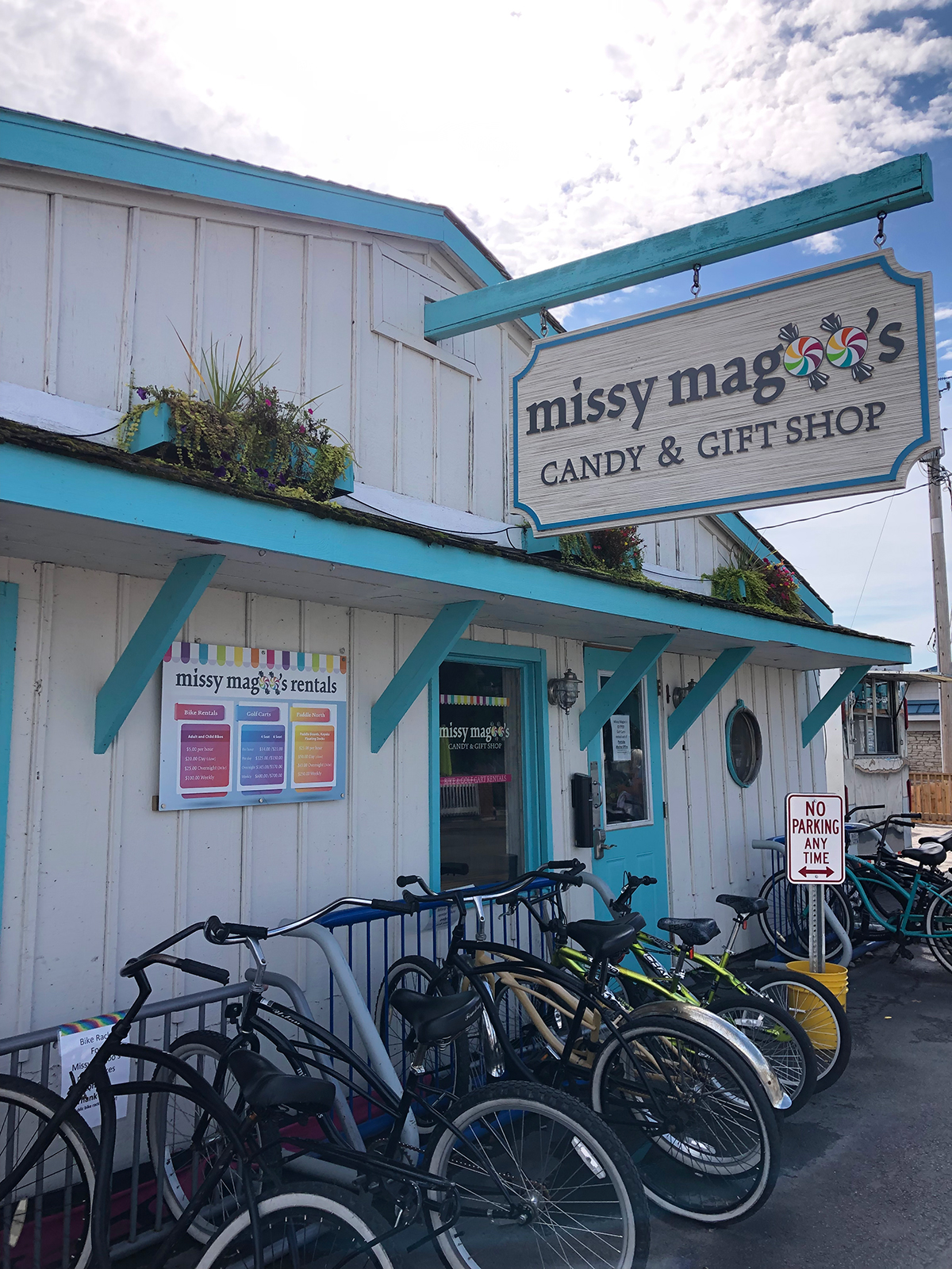 teal and white building with bikes in front sign that reads missy magoo's candy and gift shop