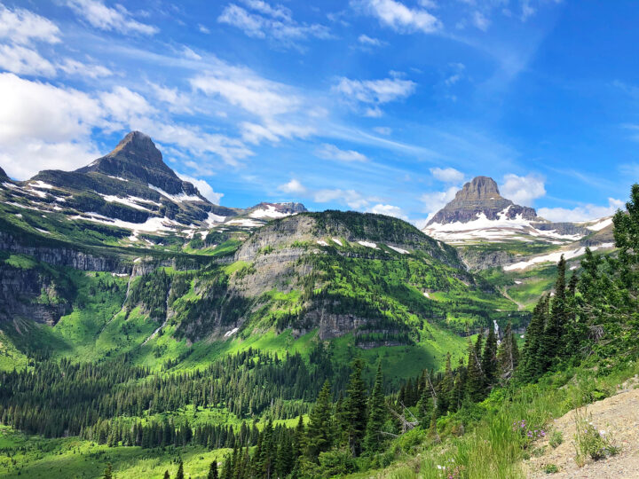 things to do in glacier national park picture of mountainside with peaks, snow green lush hills and blue sky