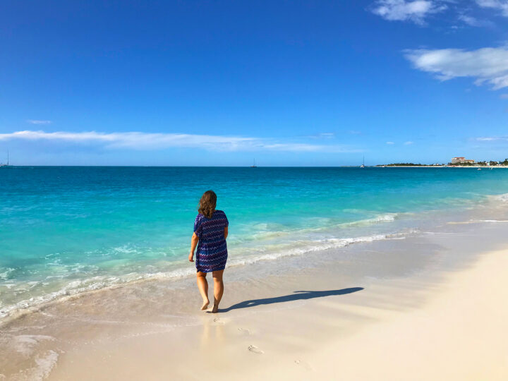 things to do in turks and Caicos woman walking on beach towards teal water white sand blue sky