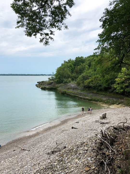 Kelleys island state park beach from above with green water rocky shore and trees lining lake