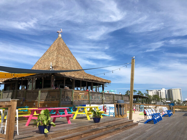 orange beach restaurants on the water large tiki hut with colorful chairs and dock