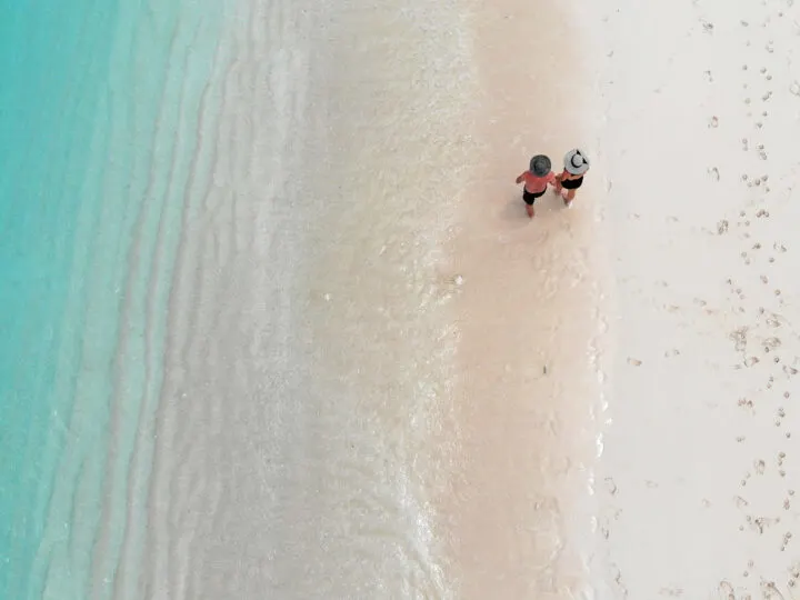 turks and caicos travel bucket list couple walking on a beach shot from above white sand teal water