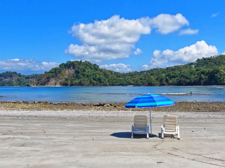 chairs and umbrella on playa biesanz gray sand blue ocean green hills
