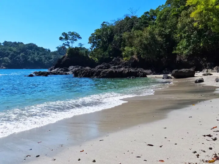 playa gemelas beach sand with rocks, green trees and blue water