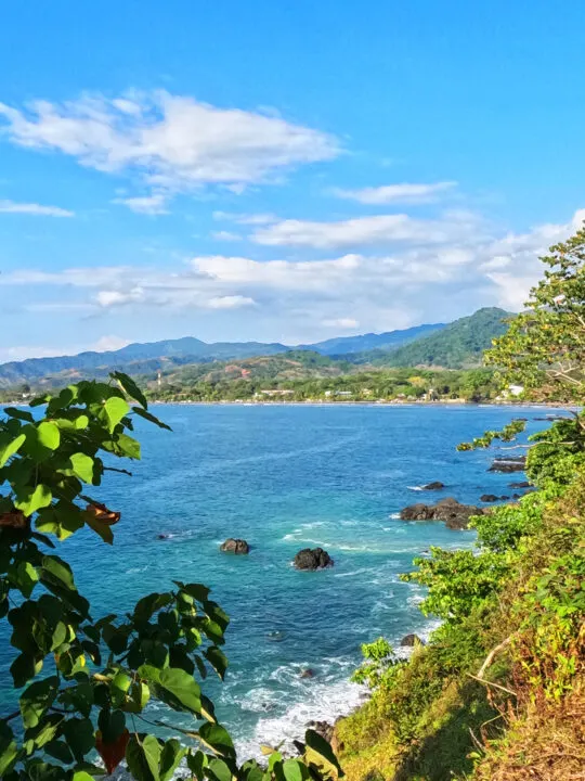 coastline with blue water green in foreground and hills in distance