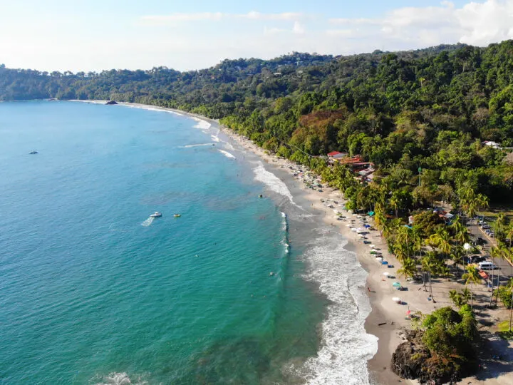 7 days Costa Rica itinerary picture of busy beach aerial view with hilly coastline teal water white waves
