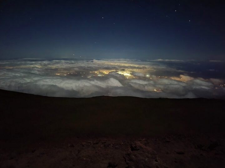 Haleakala sunrise vs sunset view of island of Maui looking down over clouds at night