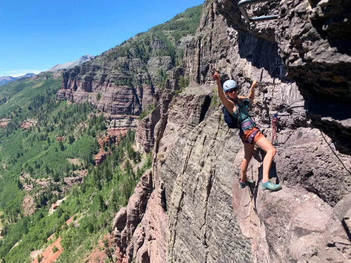 adventures in the US view of Telluride via Ferrata woman rock climbing with cliff in distance