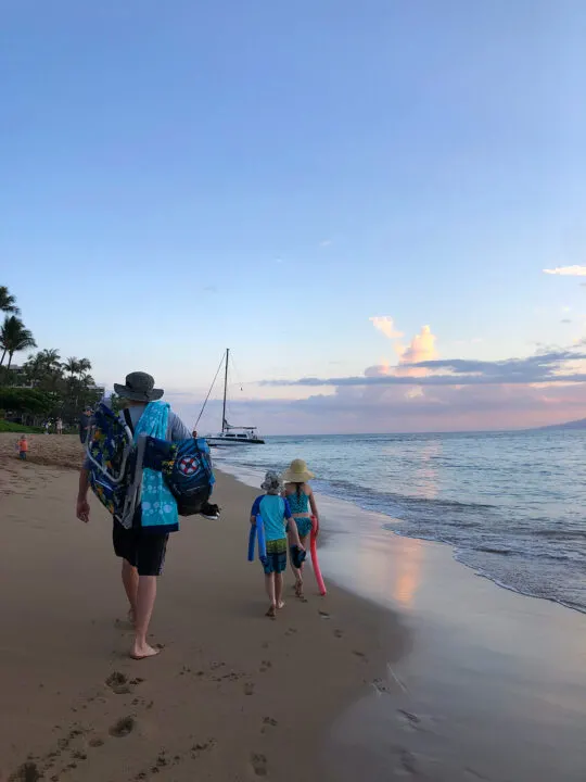 man and kids walking on beach at sunset