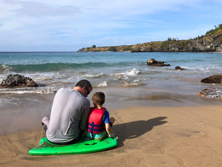 man and boy sitting on boogie board near ocean best things to do with kids in maui