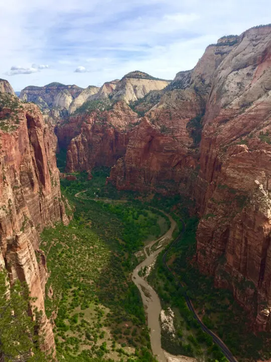 view of Zion from Angels Landing steep red canyon walls with river and trees below