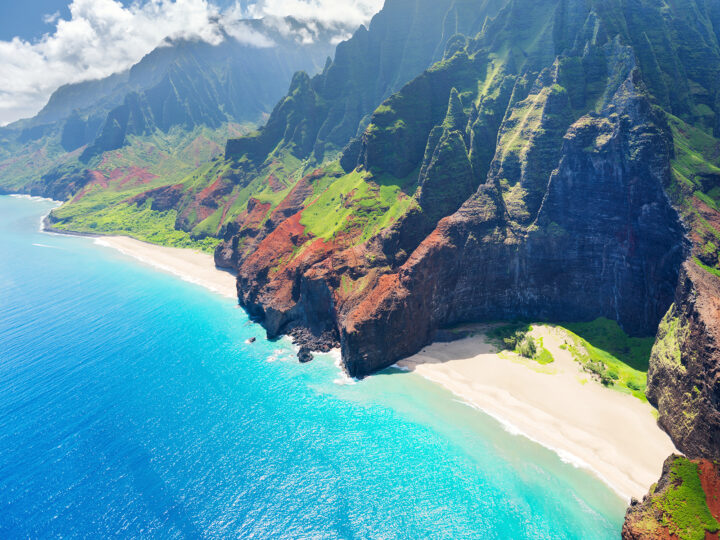 adventurous places to visit view of napali coast jagged peaks beaches and vibrant blue water