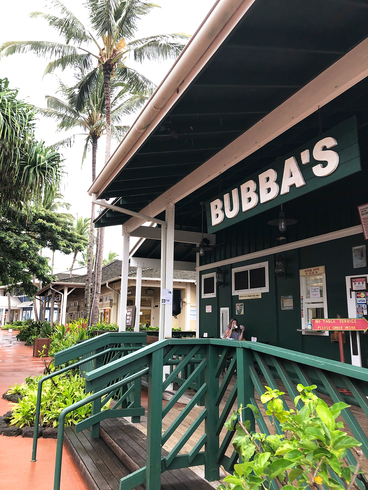 entrance to bubbas with green painted railing and buildings in background with palm trees