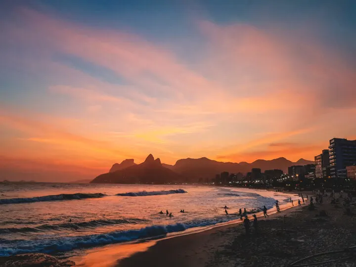 dark sunset with glow behind mountains city skyline and beach in foreground