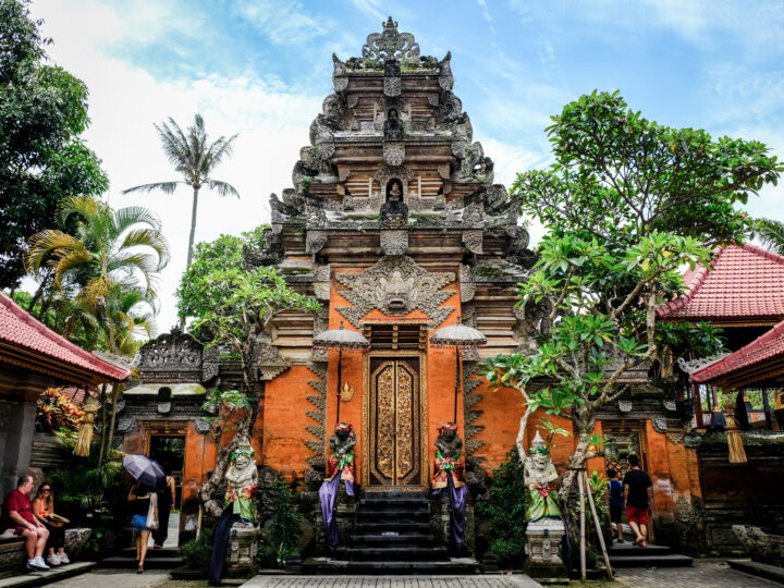 large ancient temple with trees and visitors in Bali Indonesia