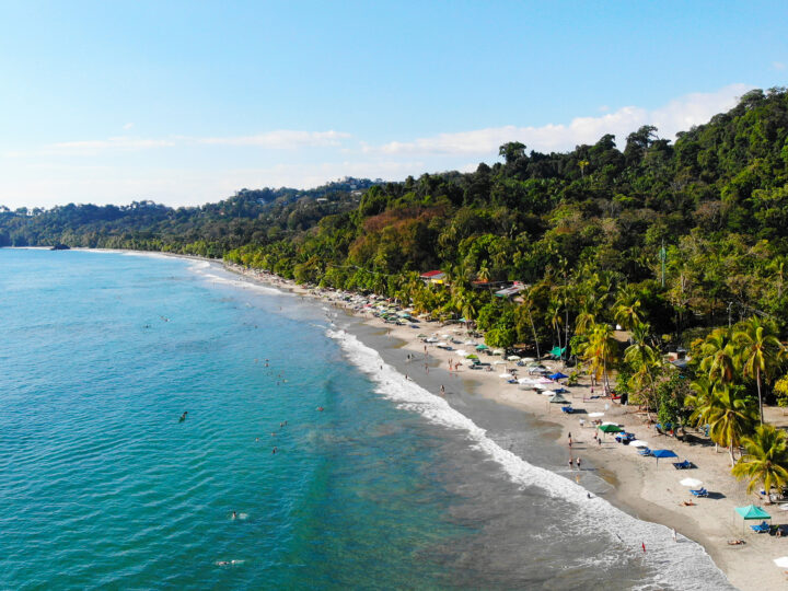 Christmas vacations for families view of Costa Rica beach from above with blue water palm trees beach tents