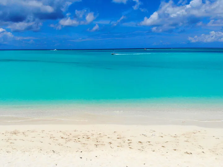 Christmas vacation ideas view of white sand beach teal water and boats in distance