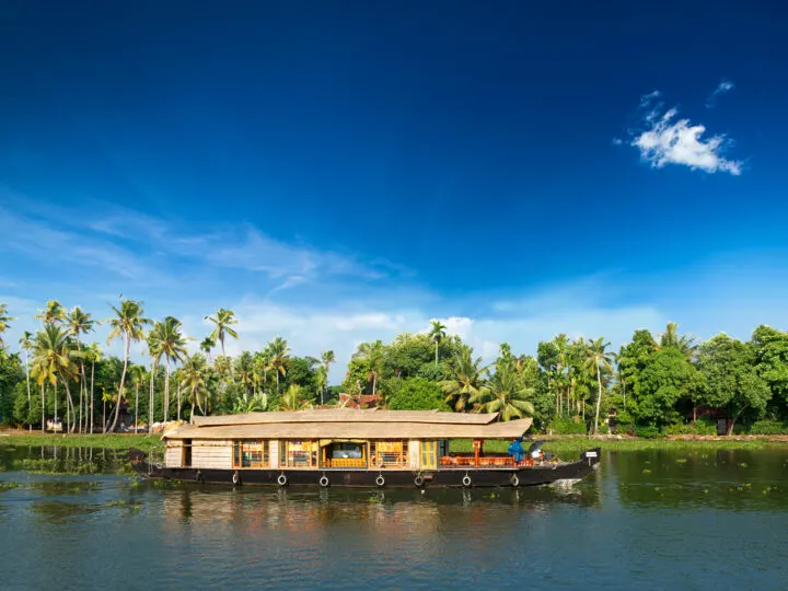 Kerala house boat on river with palm trees in background