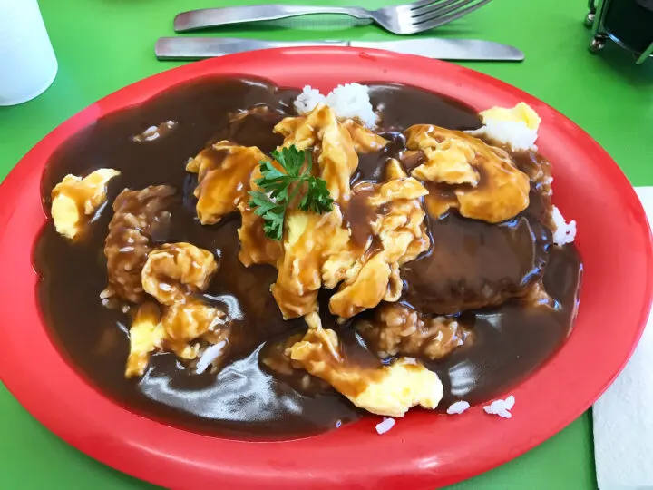 loco moco hawaii with meat gravy and rice on red plate