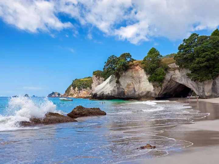 beach with rocks and cave on sunny day