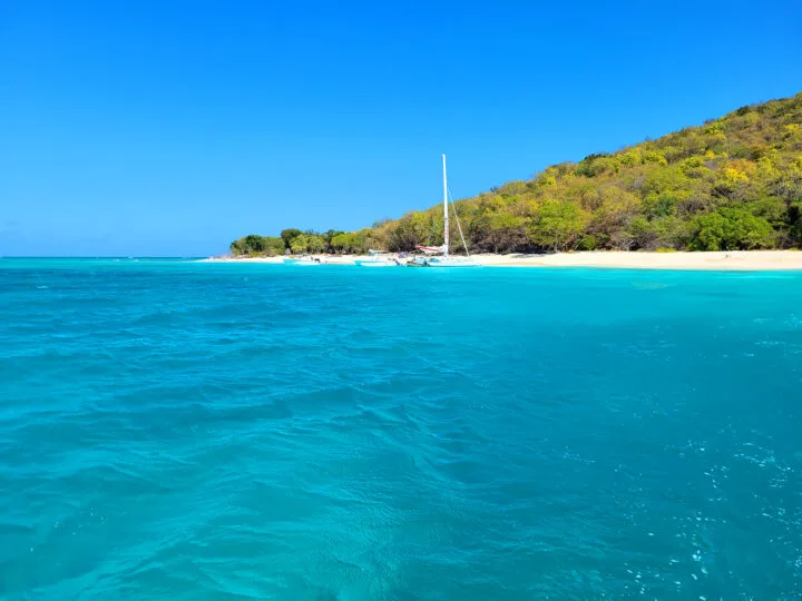 holiday vacation ideas view of St Croix bright blue water beach with catamaran and hillside