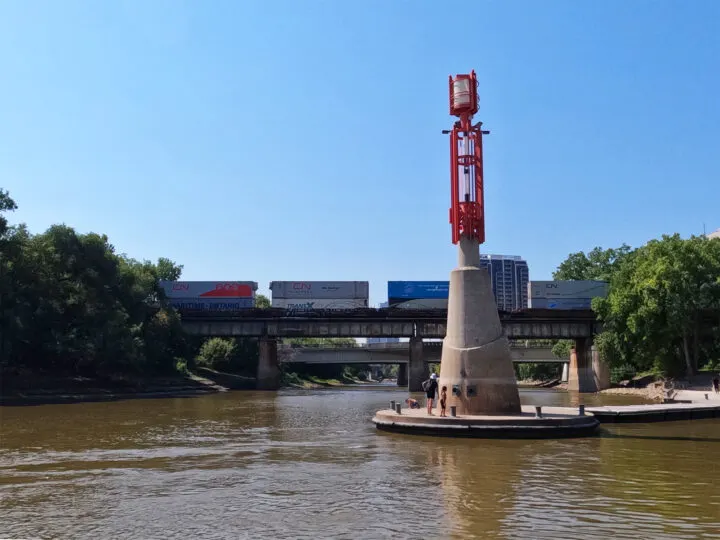 The Forks Winnipeg river with statue and bridge in distance