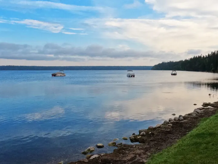 reflective lake surface with boats and rocky shore at Clear Lake Manitoba