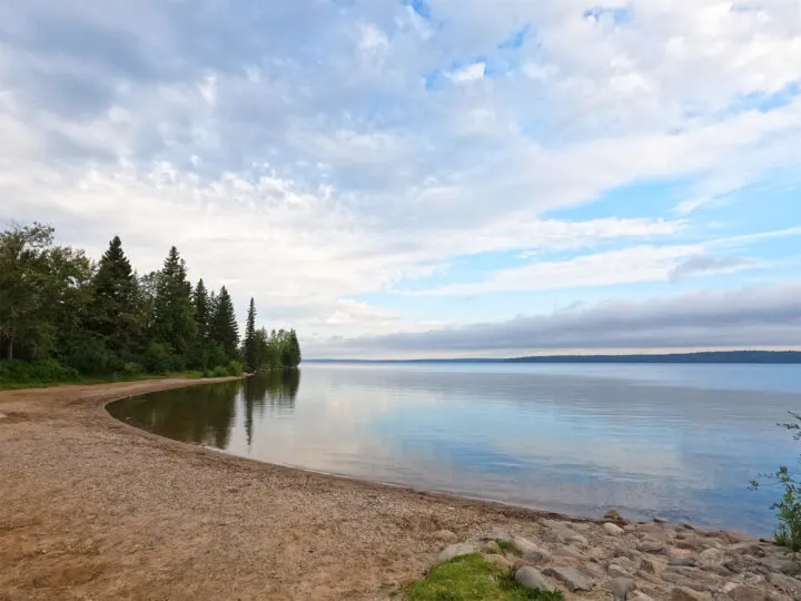 clear lake manitoba beach and trees with reflective lake