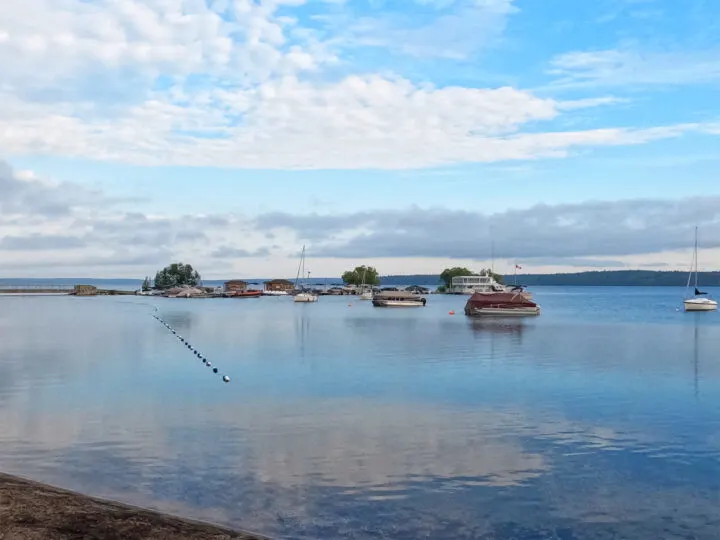 clear lake manitoba with swimming divider and boats on sunny day