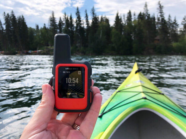 hand holding mini electronic device with kayak on lake