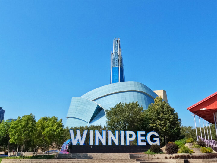 things to do in winnipeg view of winnipeg sign with large building in background on sunny day