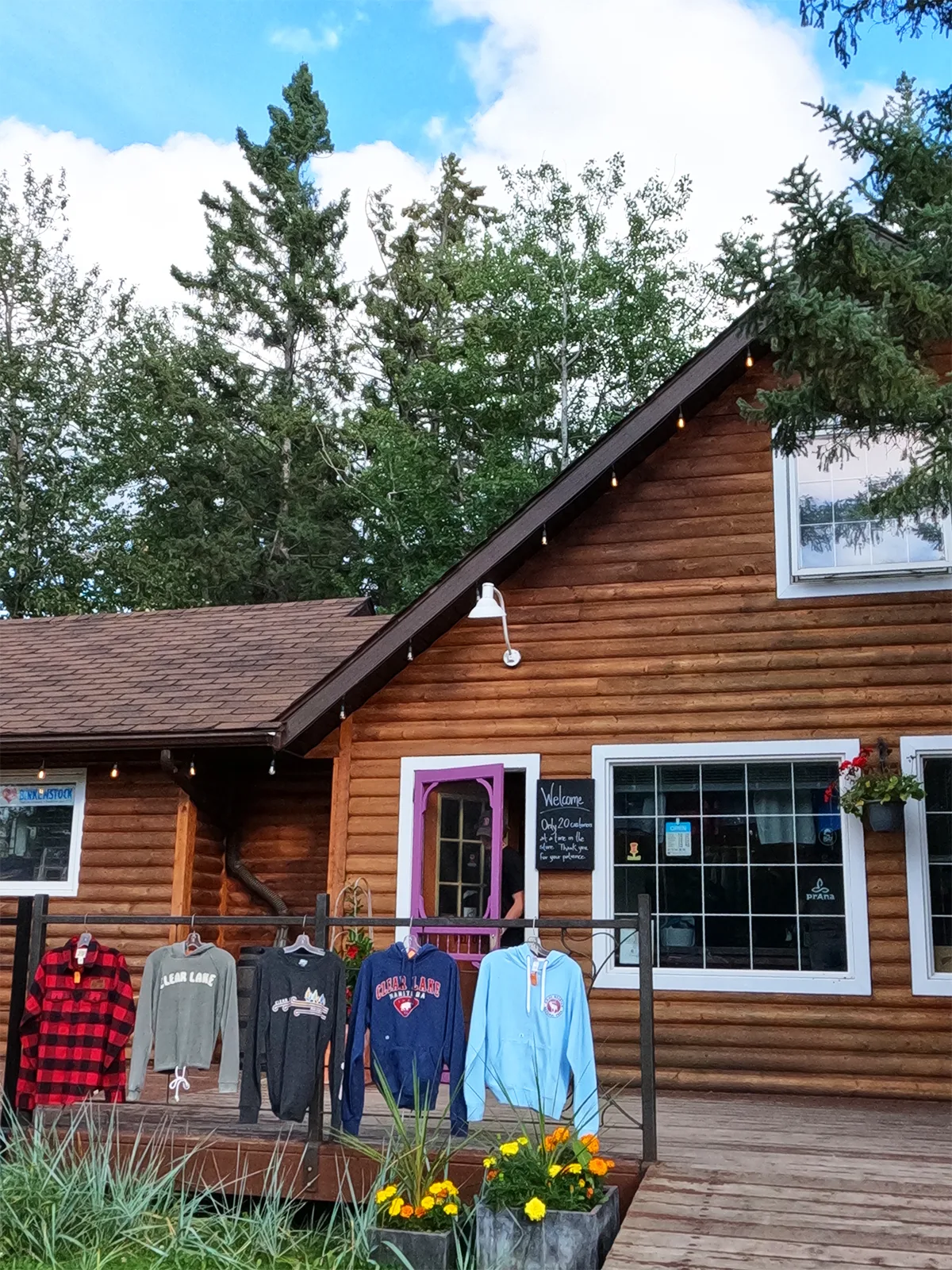 rustic shopping building with wood log cabin and shirts hung out front