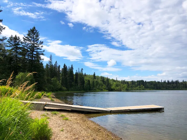 manitoba vacation view of lake with dock and trees with white clouds in sky