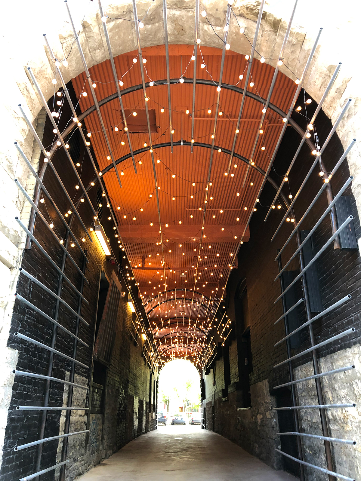 things to do in winnipeg view of tunnel in exchange district with lights and stone walls with bars