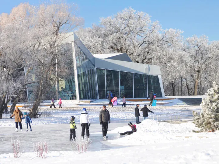 ice skating on pond with frosted trees and building in distance