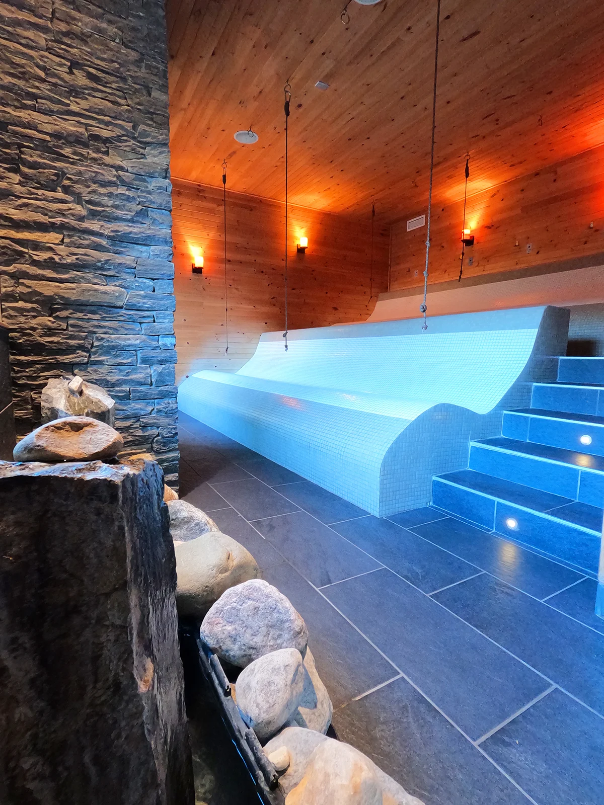 things to do in winnipeg view of sauna with rock formation curved bench in wooden and tile room