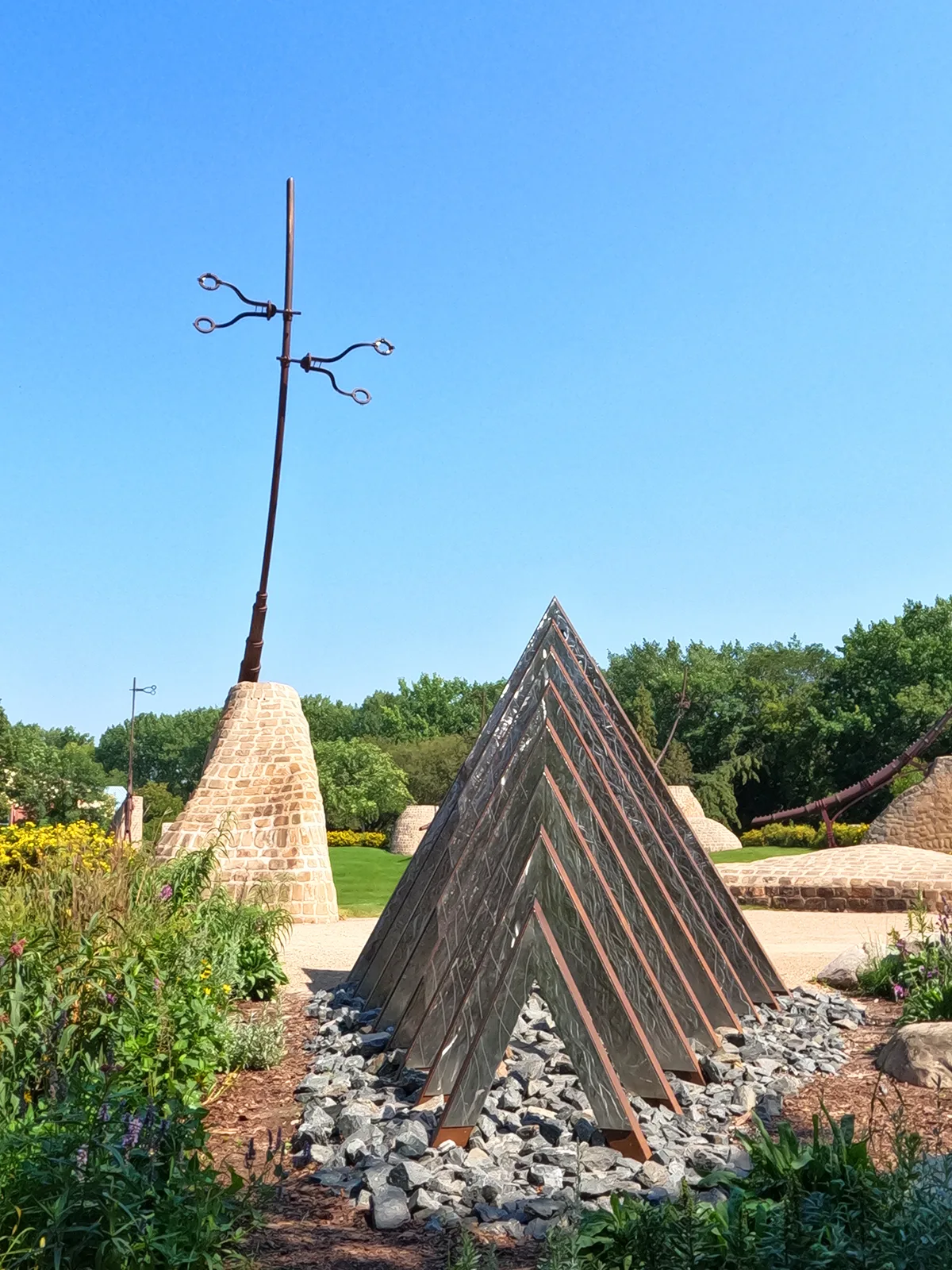 the forks artwork in winnipeg metal statues in rock with garden in distance