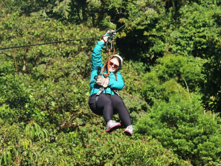woman on zipline with black pants teal jacket Costa Rica itinerary 7 days