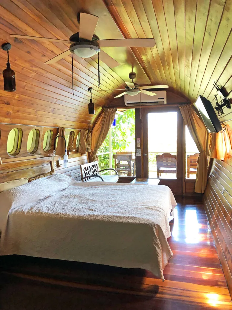 inside of airplane converted to hotel with bed tv fans and wood panels