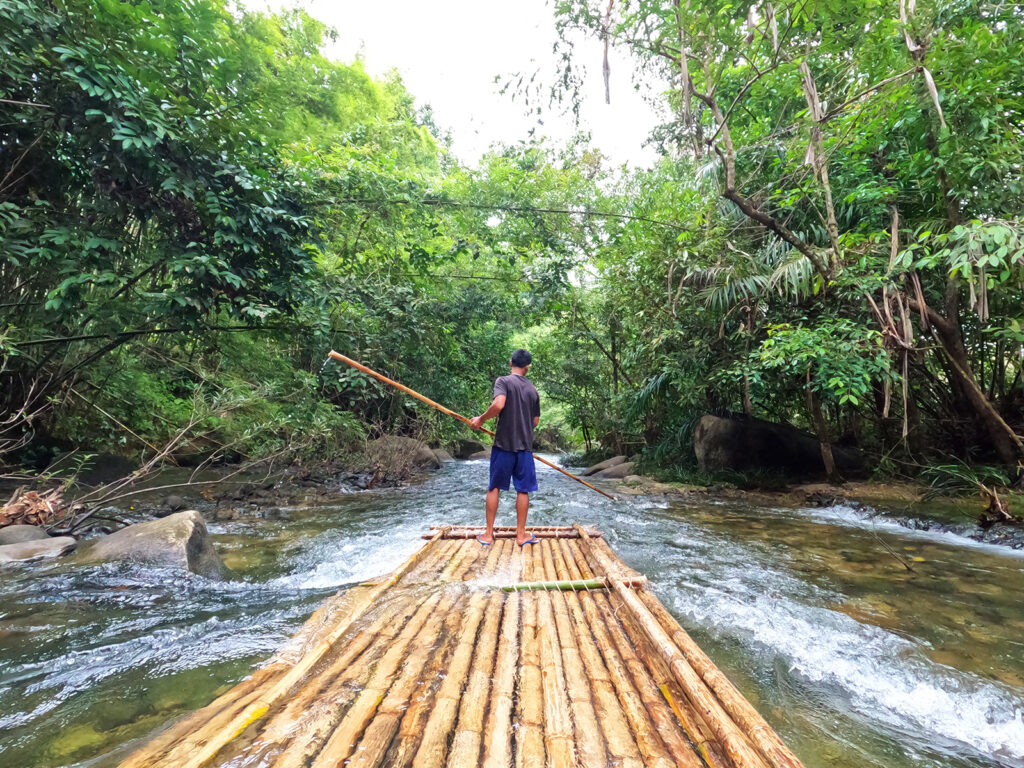  bamboo raft with man standing on it guiding down riverq