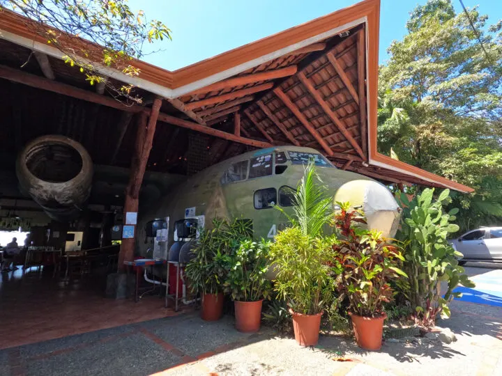 things to do in Manuel Antonio view of old airplane with plants and roof overtop