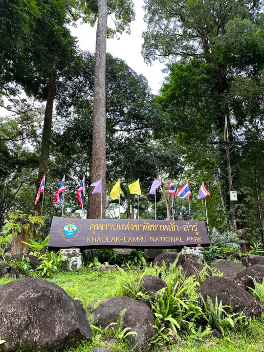 photo of khaolak-lamru national park entrance sign with flags and trees