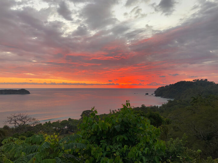 what to do in Manuel Antonio watch the vivid sunset with red and pink sky along ocean coastline