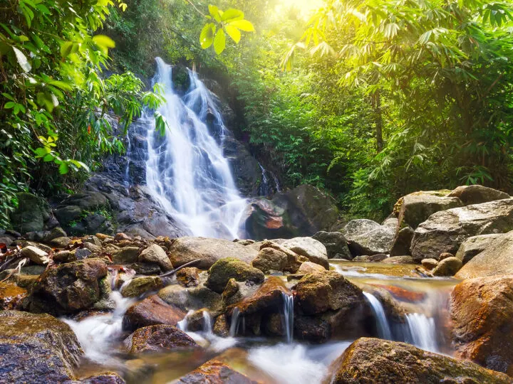 things to do in khao lak san rung waterfall rolling down rocks with trees surrounding