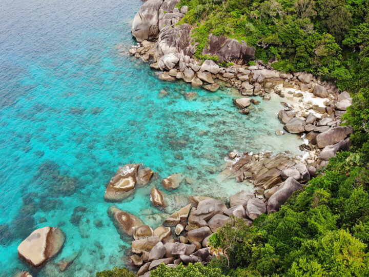 similan island thailand looking down at cove teal water rocky shore lush vegetation