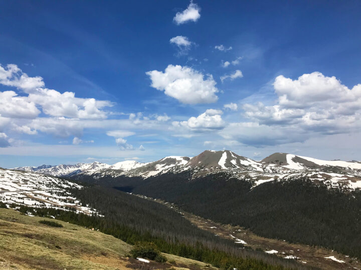 spring break ideas for families on a budget view of colorado mountains with white snow peaks blue sky puffy clouds