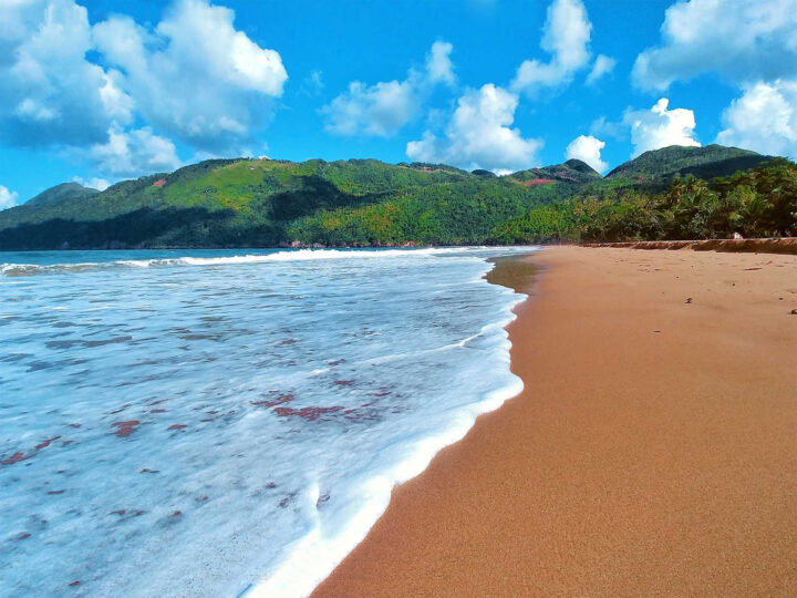 spring break destination for families view of beach tan sand white wave and mountainous coastline