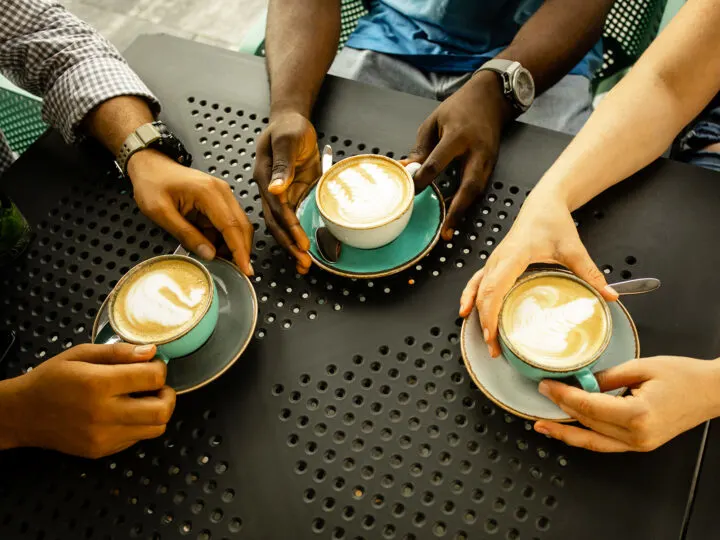 three people holding coffee on black table things to do in winter for free