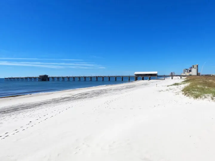 white sand and pier on sunny day in gulf state park AL