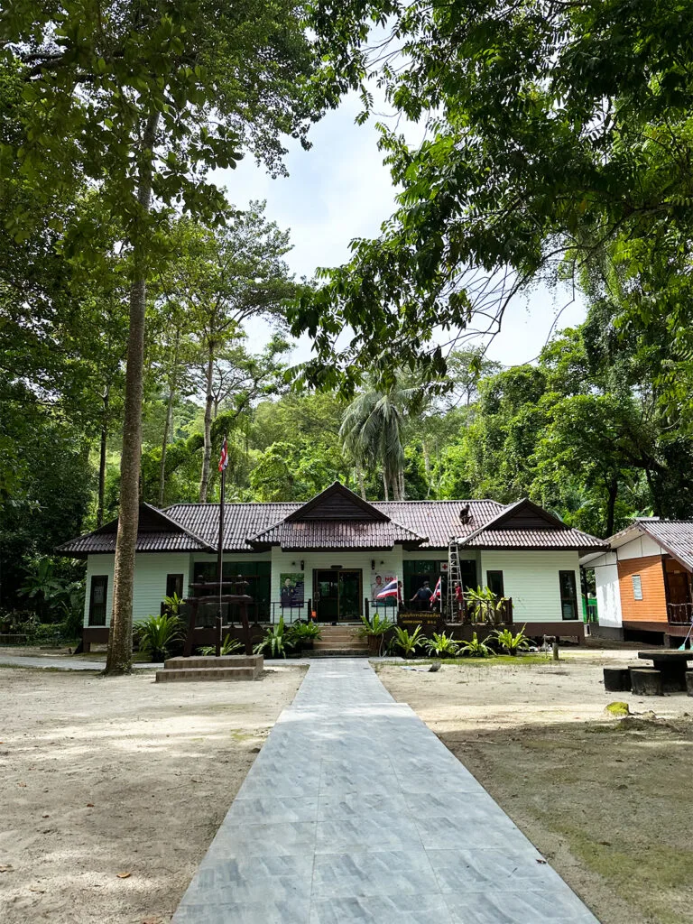 visitor center with view of tan building with sidewalk leading up to it trees surrounding